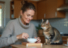 Femme en homewear remue la nourriture pour chat avec son chat tabby